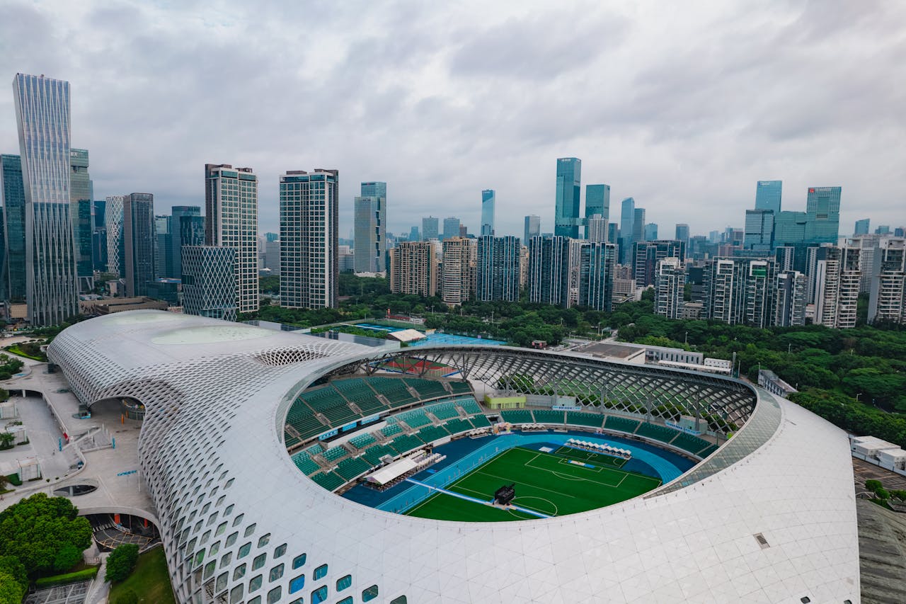Stunning aerial shot of Shenzhen's modern stadium surrounded by skyscrapers, showcasing urban architecture and cityscape.